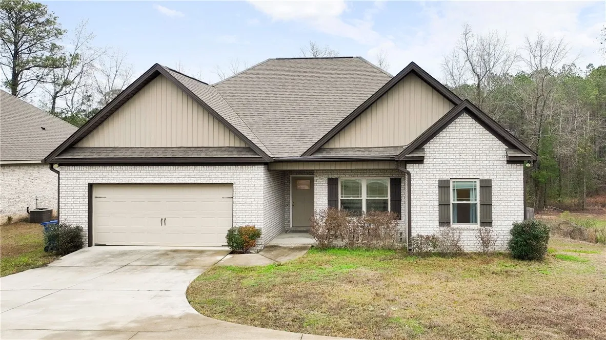 A charming single-story residence with a tan brick exterior and an attached garage.