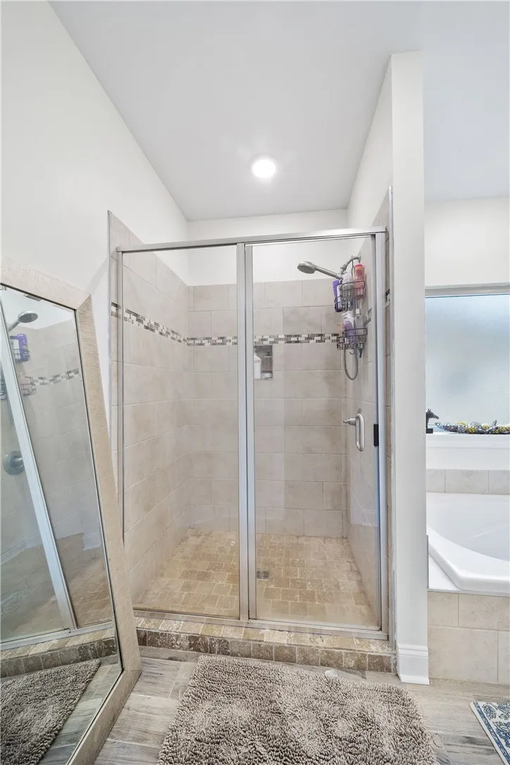 A well-lit, tiled shower enclosure with a glass door offers a revitalizing bathing experience.