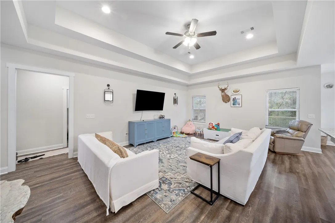 Recessed lighting illuminates this inviting living space with durable hardwood flooring and high tray ceilings.