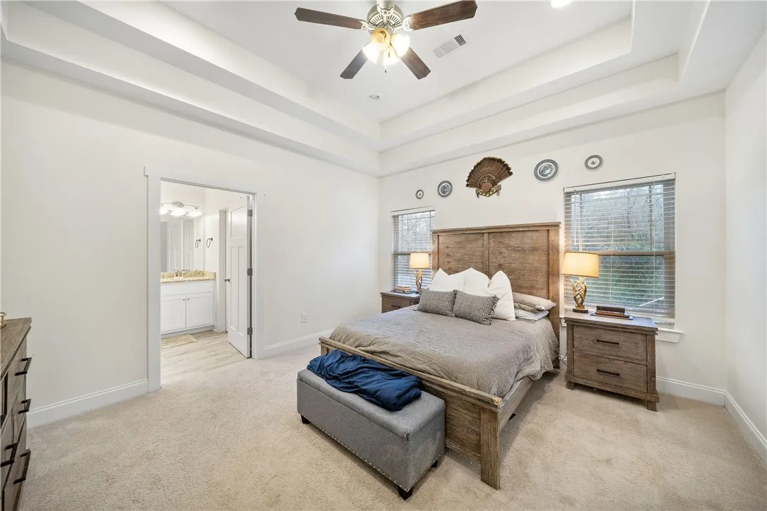 Recessed lighting and a ceiling fan create a serene atmosphere in this inviting primary bedroom.