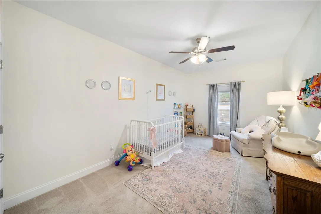A well-lit nursery offers comfort with soft carpeting and a bright window.