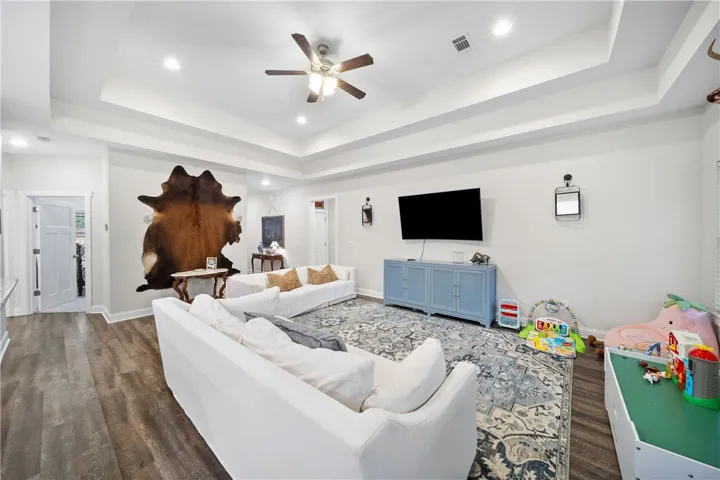 Step into a generously proportioned living room featuring elegant tray ceilings and rich wood flooring.