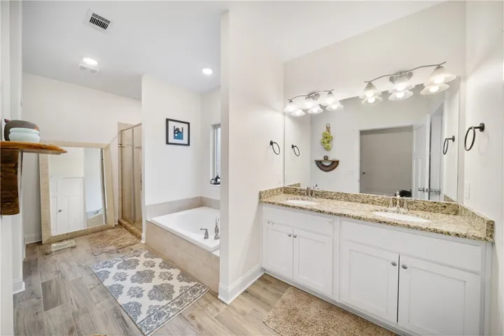 Indulge in a tranquil primary bathroom featuring a spacious dual vanity and a built-in tub.