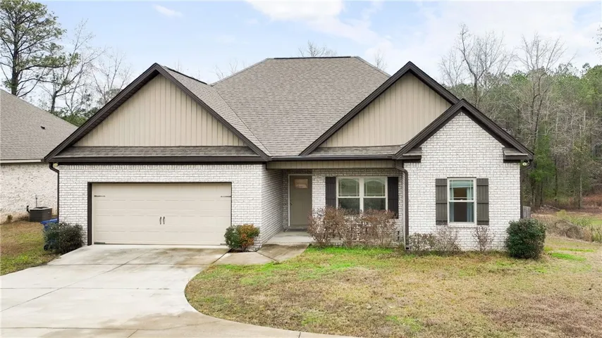 A charming single-story residence with a tan brick exterior and an attached garage.