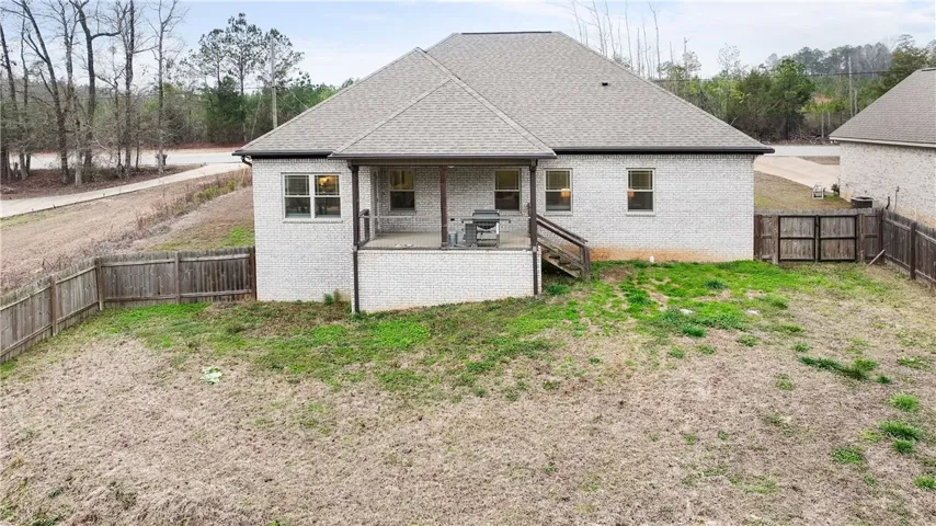 A well-maintained brick exterior home featuring a covered back patio and a fenced-in yard.