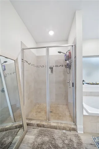 A well-lit, tiled shower enclosure with a glass door offers a revitalizing bathing experience.