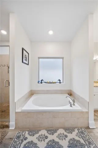 Relax in the comfort of a soaking tub within this thoughtfully designed primary bathroom.