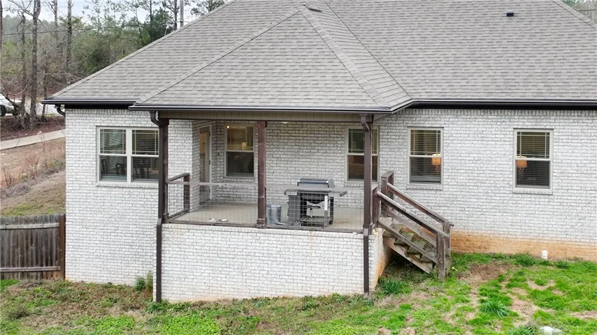 A private covered patio provides an ideal setting for outdoor dining and entertainment, overlooking the gently sloping yard.