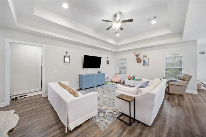 Recessed lighting illuminates this inviting living space with durable hardwood flooring and high tray ceilings.