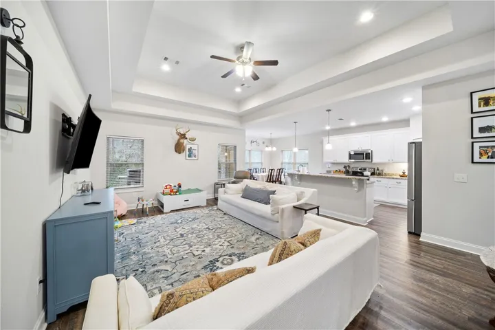 An open concept living area boasts a tray ceiling and durable hardwood flooring.