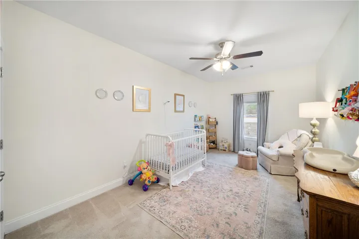 A well-lit nursery offers comfort with soft carpeting and a bright window.