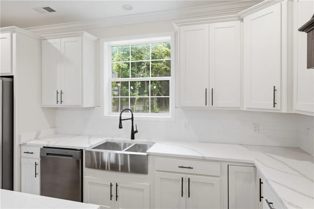 White cabinetry and quartz countertops elevate this well-appointed kitchen.