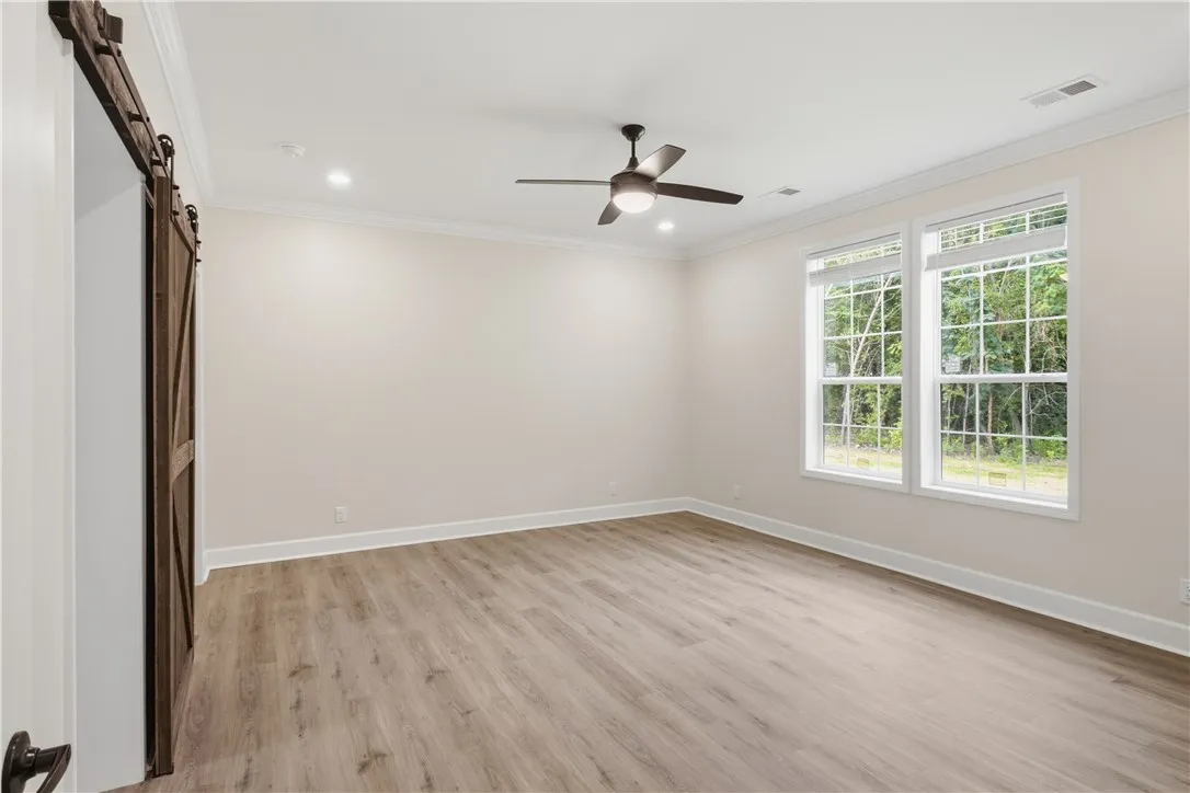 A versatile space features modern wood flooring, recessed lighting, and a charming barn door entrance.