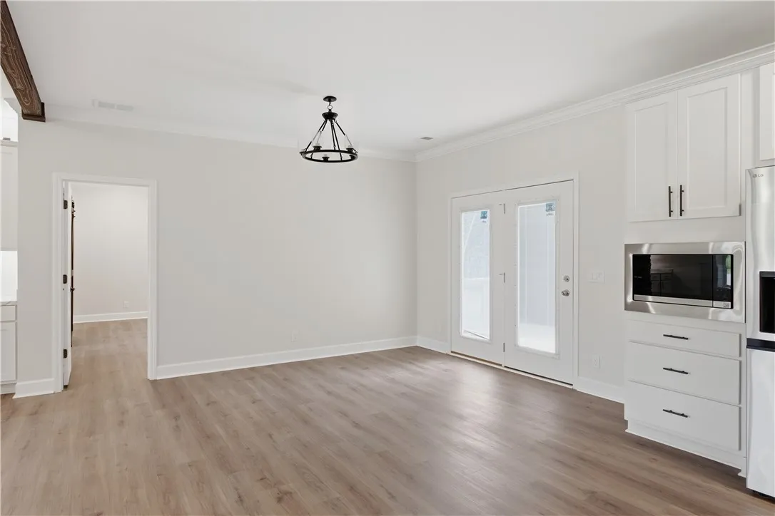 A well-lit area featuring durable wood flooring, modern ceiling lighting, and patio door access.