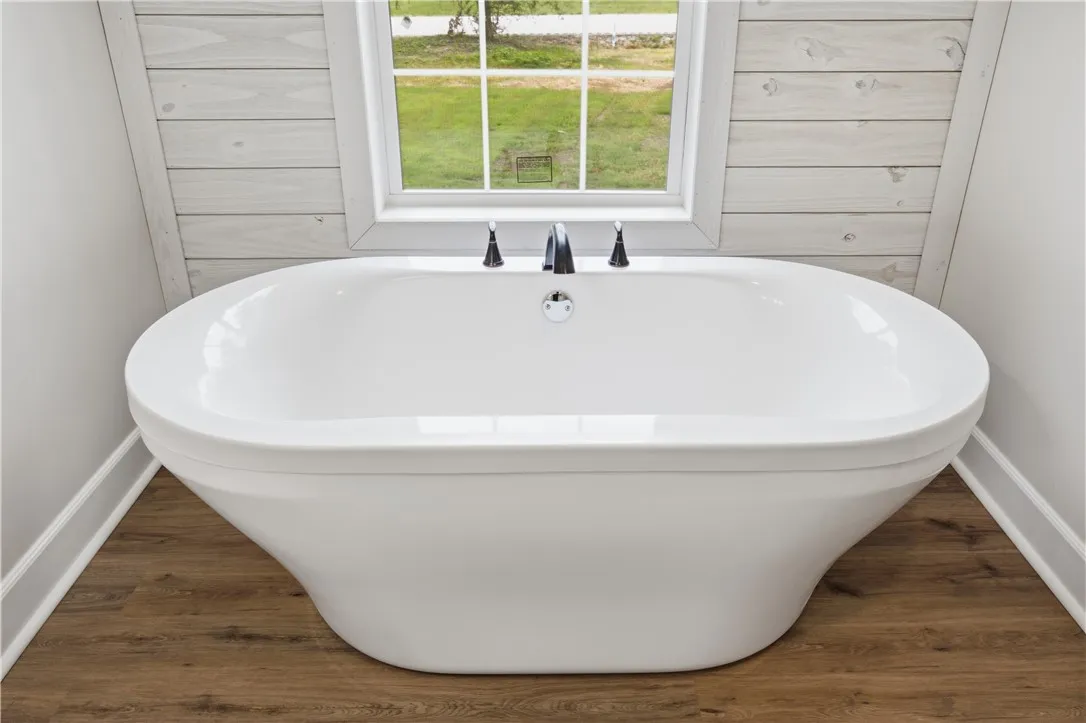 A spacious soaking tub positioned beneath a window offers serene views of the outdoors.