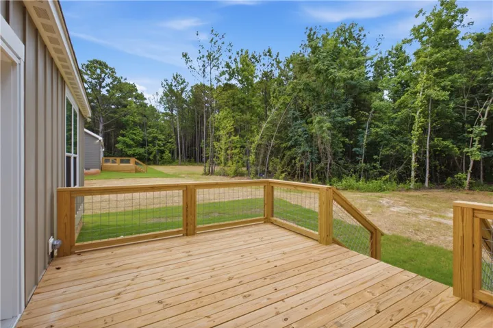 A spacious wooden deck provides ample outdoor living space, overlooking a natural, treed landscape.