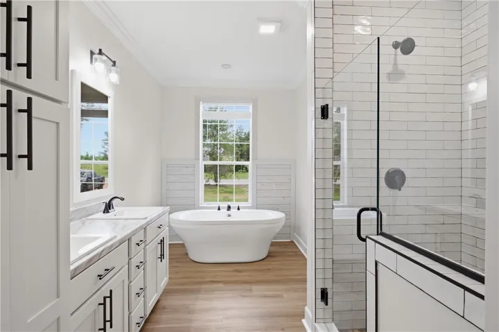 A pristine bathroom featuring a standalone soaking tub and an elegant tiled shower with glass enclosure.