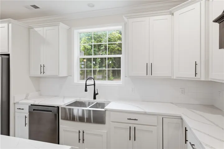 White cabinetry and quartz countertops elevate this well-appointed kitchen.