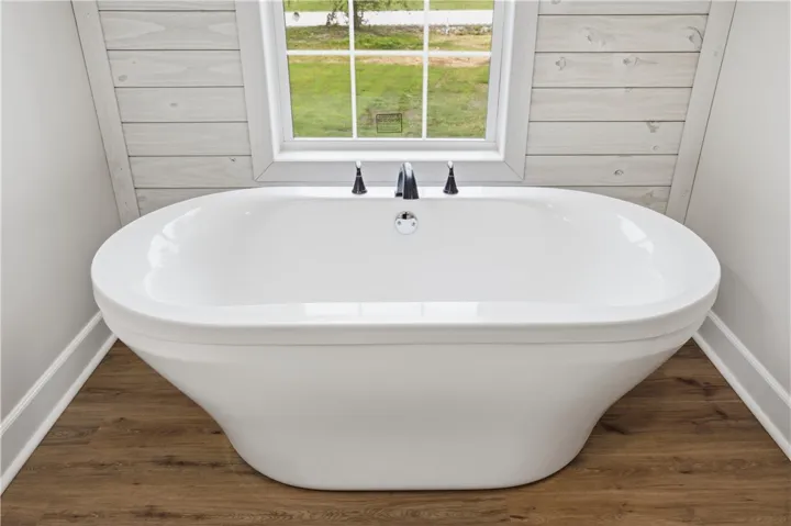 A spacious soaking tub positioned beneath a window offers serene views of the outdoors.