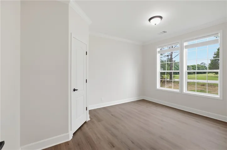 Sun-filled room boasts abundant natural light, crown molding, and resilient flooring.
