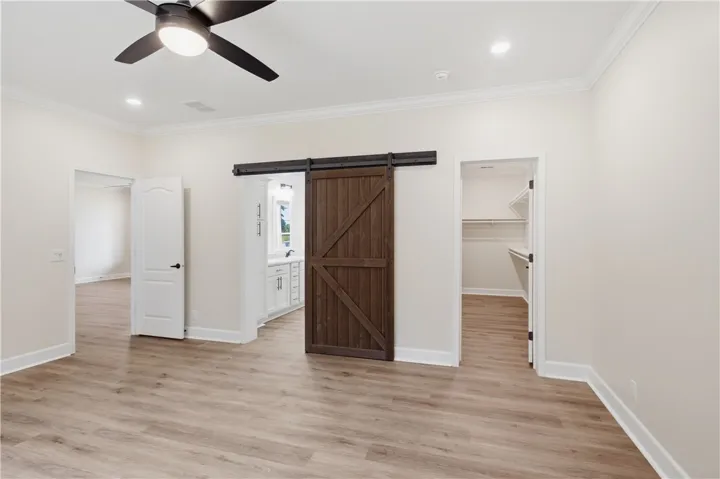 A rustic barn door adds charm to this primary bedroom with durable wood flooring.