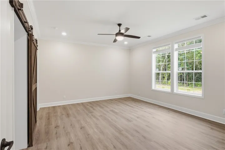 A versatile space features modern wood flooring, recessed lighting, and a charming barn door entrance.