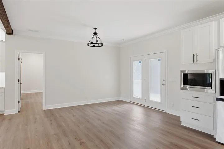 A well-lit area featuring durable wood flooring, modern ceiling lighting, and patio door access.