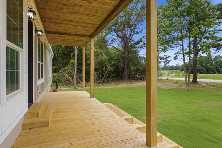 A spacious wooden porch offers peaceful views of the surrounding natural landscape and open yard.