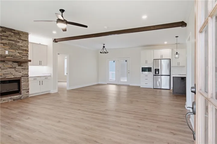 An open concept living area featuring a stacked stone fireplace and light-toned flooring.