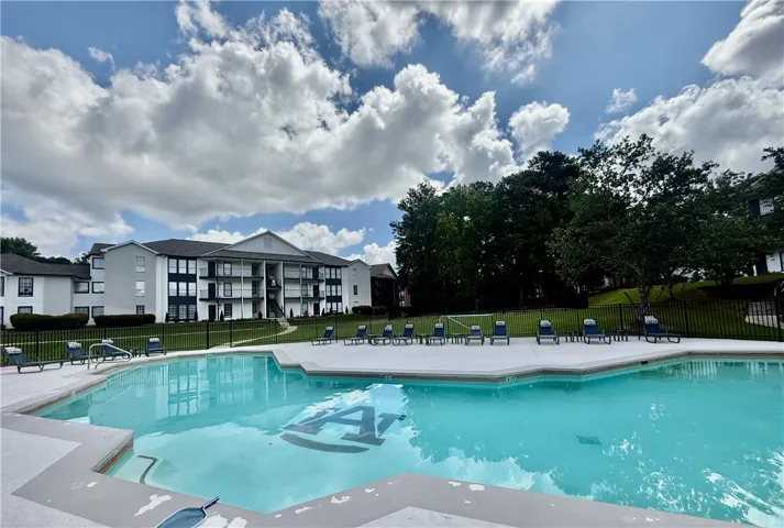 Lounge poolside with apartment views and lush landscaping.