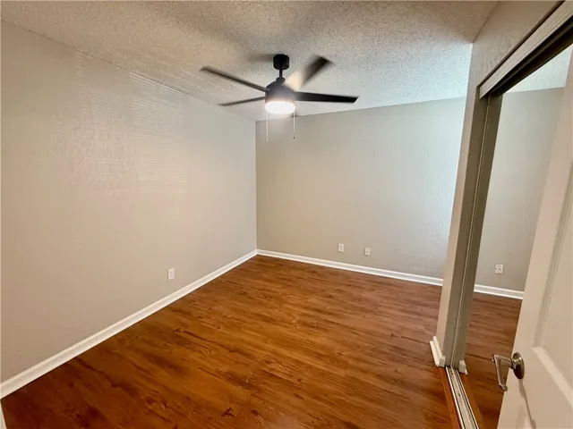Rich hardwood-style flooring extends through this serene space, featuring a modern ceiling fan for comfort.