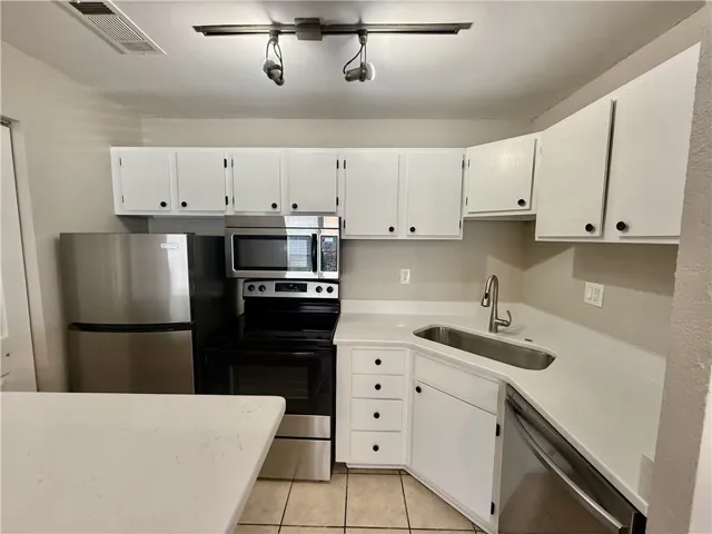 A well-appointed kitchen features white cabinetry, quartz counter tops and sleek stainless steel appliances.