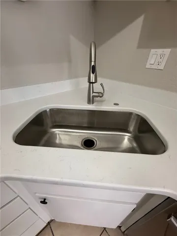A deep stainless steel sink with an elegant pull-down faucet is seamlessly integrated into stone counters.