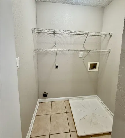 Functional utility space with tiled flooring and convenient wall-mounted shelving for organized storage.