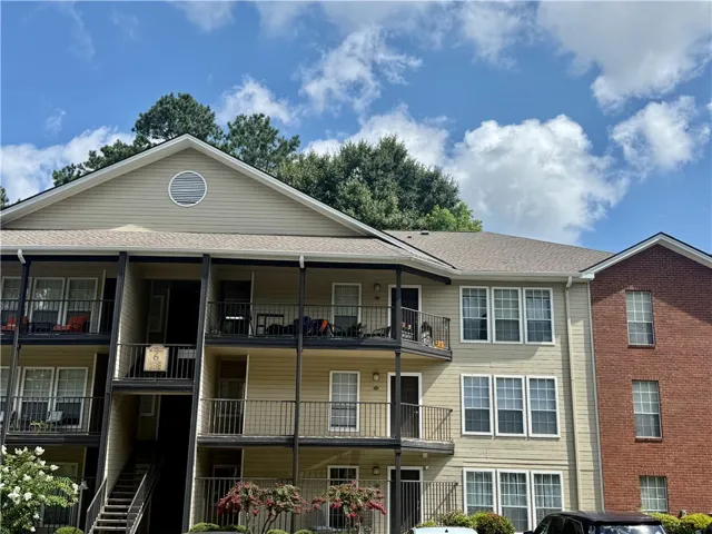 Multi-level residential building offers private balconies and brick accents under a bright sky.