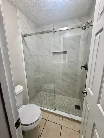 A sleek, tiled walk-in shower features a contemporary sliding glass door and ample space.