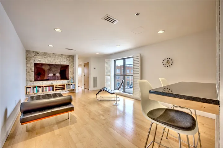 Hardwood floors and bright recessed lighting illuminate this open-concept living space, featuring a window with street views.