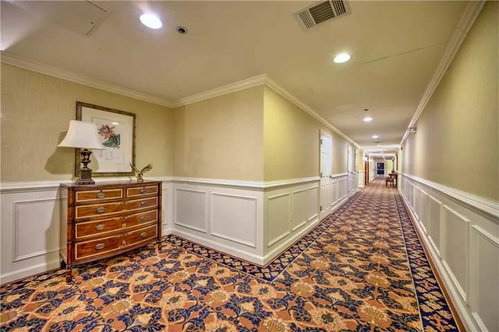A well-lit corridor boasts intricate patterned carpeting and classic wainscoting.