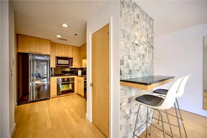 A sleek modern kitchen with light wood cabinetry and integrated appliances.