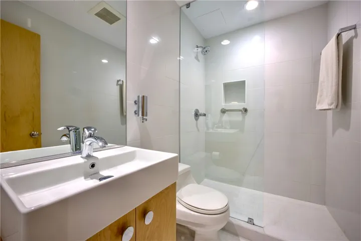 A well-lit bathroom features a modern vanity with a rectangular sink and a sleek glass-enclosed shower.