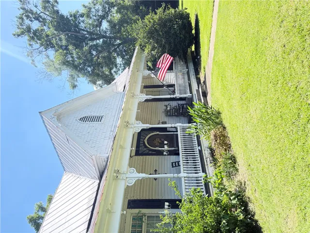 A charming two-story home with a wide front porch and a neatly kept green yard.