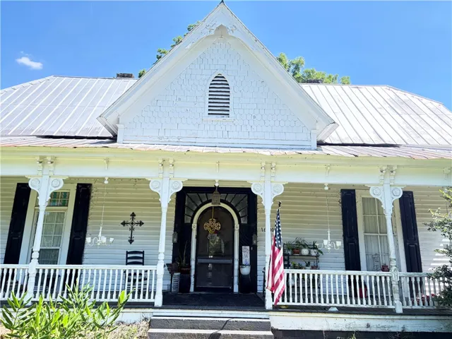 A charming Victorian-style facade boasts intricate porch detailing and a classic metal roof.