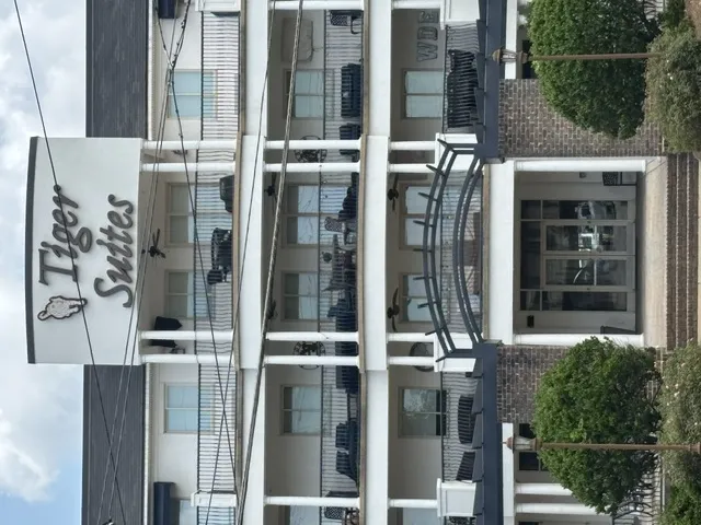 A prominent sign adorns the façade of this multi-level residential building, featuring classic white columns and inviting balconies.