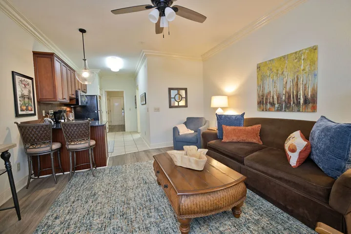 Rich wood cabinetry and classic crown molding elevate this open-concept living area and kitchen entry.