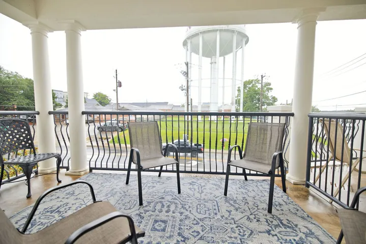 Stately white columns and a classic wrought-iron railing frame this covered outdoor porch.