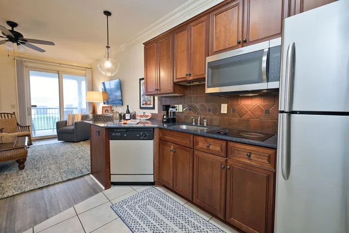 Rich wood cabinetry and stone counters anchor this kitchen opening directly to the living area.