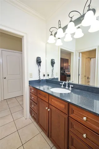 Gleaming stone countertops and classic wood cabinetry define this elegant, tile-floored bathroom.