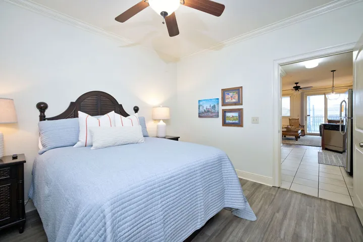 Crown molding and wood-look flooring enhance this cozy bedroom with a wide entryway.