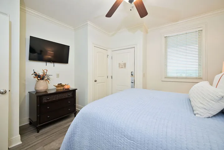 Crown molding frames the bedroom, which includes wood flooring and a classic window.