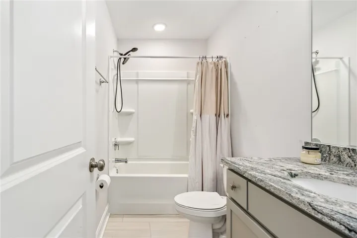 Refined bathroom offering a sleek vanity with granite counters and a clean tub-shower combination.